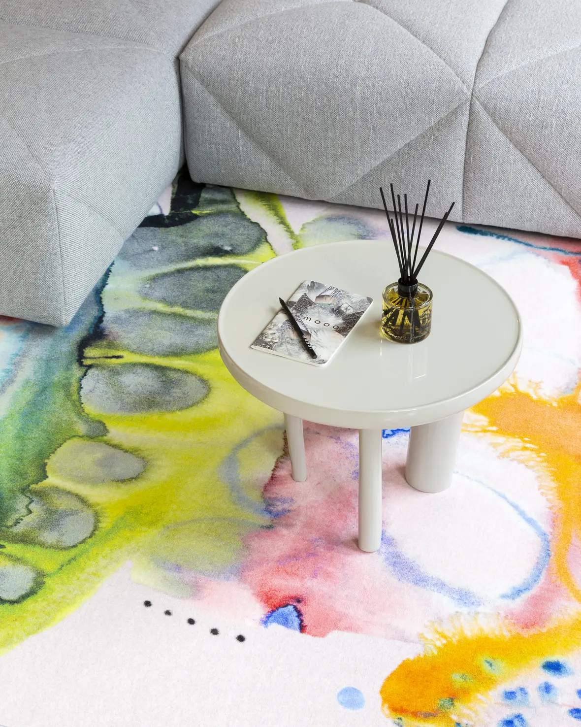 In the Meadow Bumblebee II carpet lifestyle image with room fragrance indigo hotto and notebook